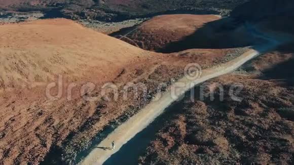 空中观景一个年轻的时髦女孩在一条通往火山的步行路线上在山上奔跑视频的预览图