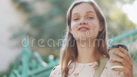 棕色头发蓝眼睛和雀斑的年轻快乐白种人女孩抱着咖啡杯和喝酒的迷人肖像视频的预览图