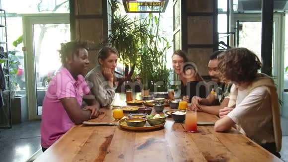 一群多元文化的朋友坐在午餐和谈话中视频的预览图