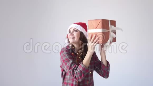 快乐美丽的女人戴着圣诞帽和睡衣摇动礼盒假日概念慢动作视频的预览图