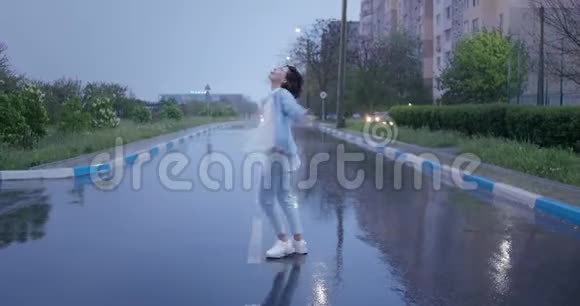 年轻积极的女孩在雨中跑步跳舞玩得很开心坏天气欢乐潮湿道路幸福短发视频的预览图
