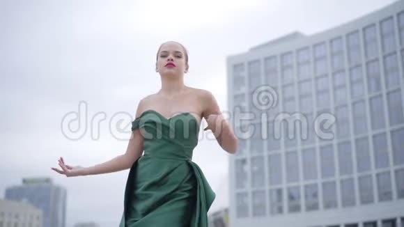美丽漂亮的姑娘穿着漂亮的晚礼服在摩天大楼附近的空城广场上翩翩起舞视频的预览图