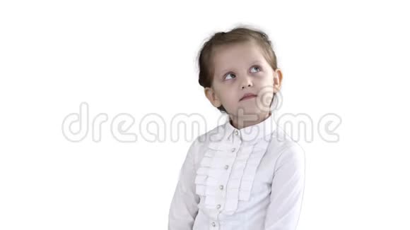可爱的学龄前女孩站在害羞的周围思考白色的背景视频的预览图