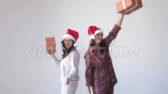 戴着圣诞帽的快乐女人在白色背景上用礼品盒跳舞假期概念视频的预览图