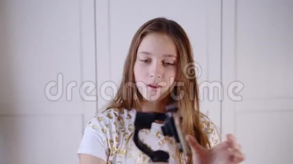 一个年轻快乐的女孩笑着用手机与朋友在线视频聊天并在社交媒体上博客视频的预览图