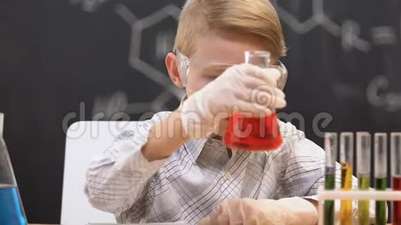 小学生看着装有红色液体的瓶子把反应数据写在笔记本上视频的预览图