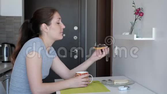 女人正在度假时在租来的公寓里的小厨房里吃早餐茶和茶视频的预览图