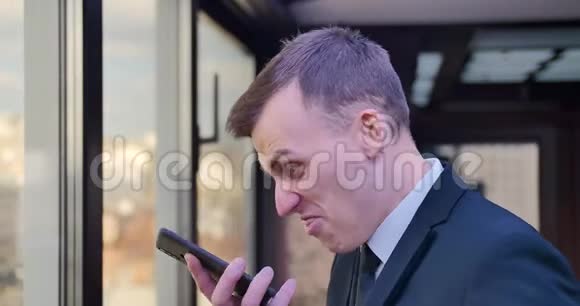 一个男商人在电话里说话做鬼脸露出舌头嘲笑对话者莫克耶视频的预览图