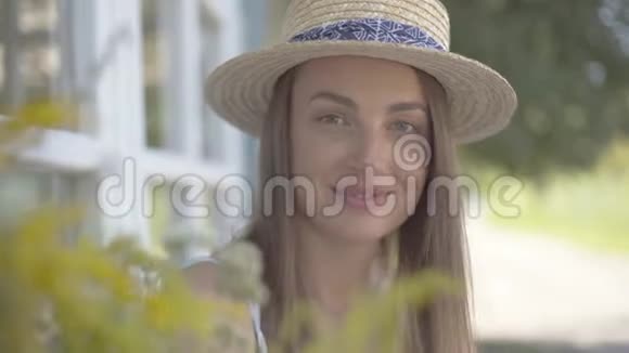 特写一张戴着草帽的可爱年轻女人的脸看着镜头在户外快乐地微笑着情感农村生活方式视频的预览图