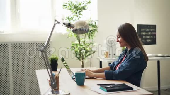 在办公室使用笔记本电脑的美女后景然后微笑着休息视频的预览图