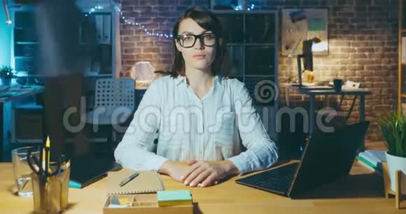 商务女士坐在办公室的办公桌前看着相机的时间流逝画像视频的预览图