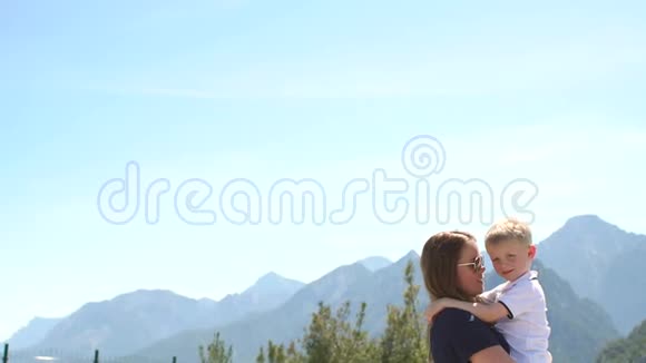 妈妈抱着一个小孩子在她的怀里在夏天的山上和天空视频的预览图