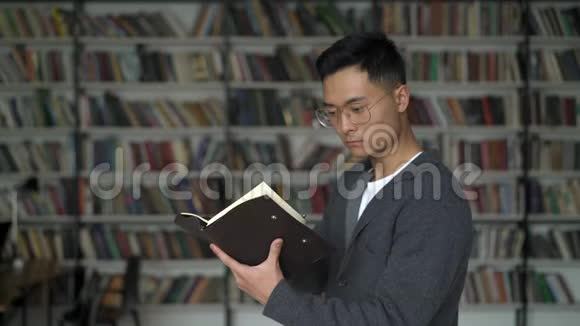 在图书馆书架的背景上一个严肃的年轻人在一张钞票上做笔记视频的预览图