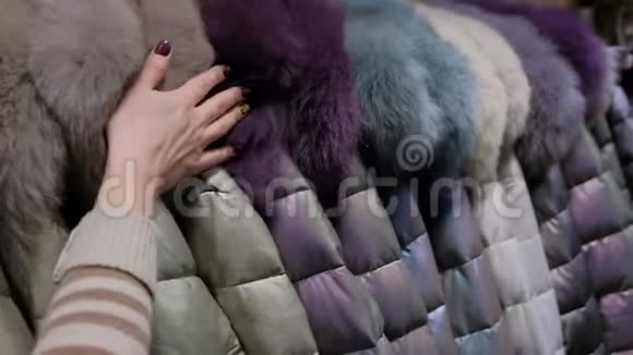 女人的手触摸一套柔软的羽绒服衣架上有引擎盖出售购物概念视频的预览图