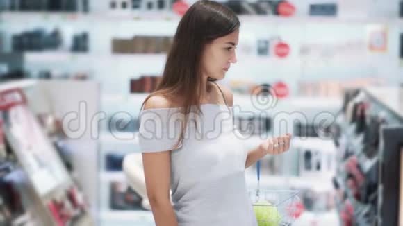漂亮的女孩在化妆品店里选择睫毛膏打开闻慢动作视频的预览图