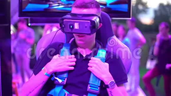 一个年轻的金发男子坐在虚拟现实技术智能手机的头盔上测试视频的预览图