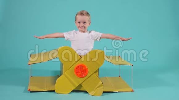 小快乐飞行员在黄色纸板飞机上飞行视频的预览图