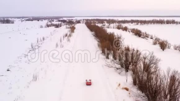 橙色汽车乘坐冬季雪道顶景视频的预览图