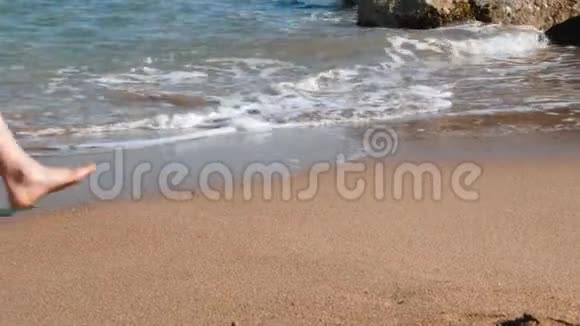 苗条的女人她的腿在黄沙上沿着大海行走在沙滩上用沙子晒黑的腿年轻苗条的女孩沿着海走视频的预览图