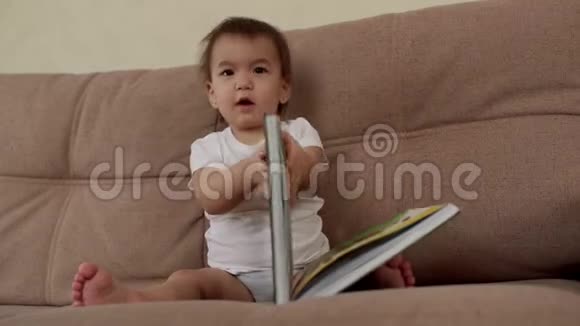 小女孩坐在沙发上寻找书中的正确页面视频的预览图