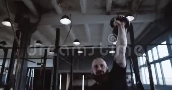 极限功能训练运动年轻的白种人男子在锻炼时举水壶铃在大型健身房缓慢运动视频的预览图