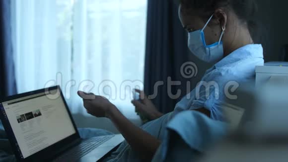 戴口罩的女人在大流行期间被电脑隔离在家中女人用防腐剂处理双手然后继续工作视频的预览图