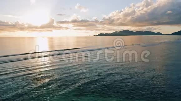 在热带岛屿的4K空中拍摄日落和海浪的镜头在水面上空低空飞行的无人机视频的预览图