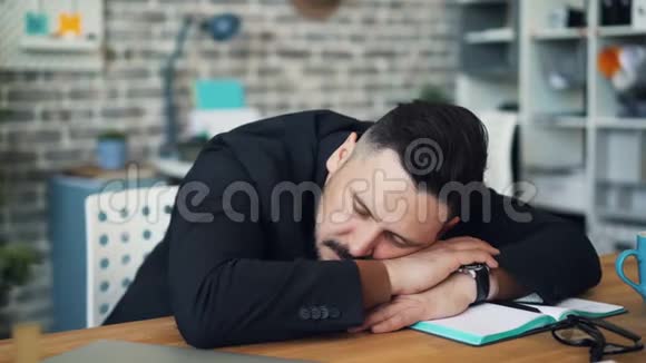 一个人坐在桌子上一个中年黑发人在工作中睡觉视频的预览图