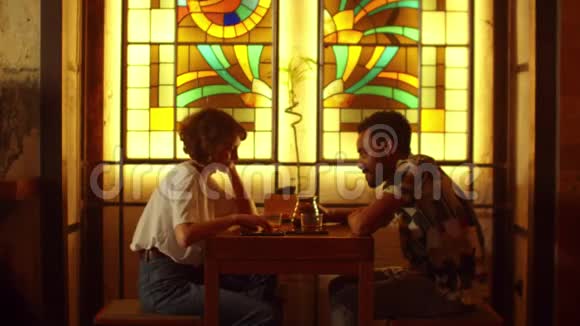年轻夫妇坐在咖啡馆的桌子旁聊天男人倒杯茶视频的预览图