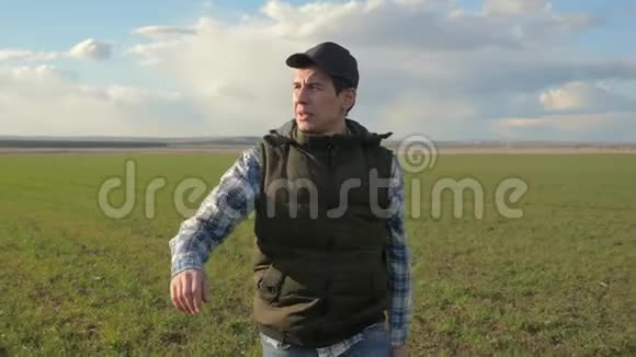 戴着帽子的农夫红脖子正走在绿色的田野上春收农业理念冬季的男性散步视频的预览图