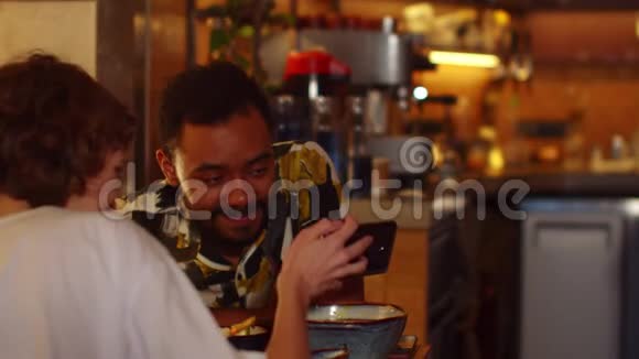 两个人坐在咖啡馆的桌子旁吃饭女孩在她的手机上显示一些东西视频的预览图