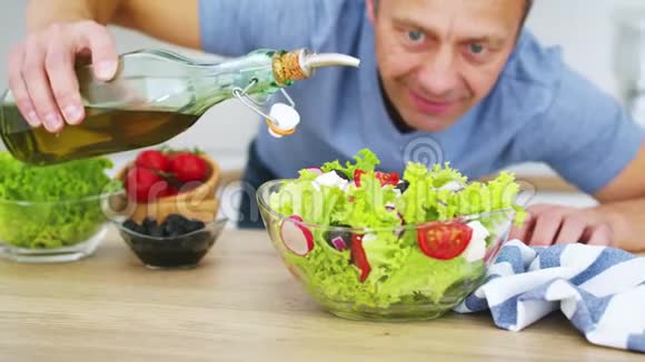 厨师把橄榄油倒入厨房的新鲜蔬菜沙拉中黑色魔术影院慢镜头视频的预览图