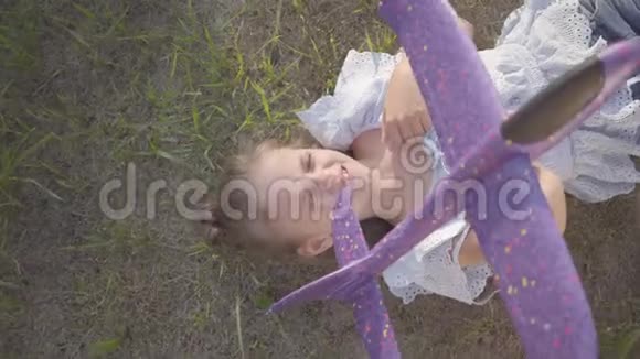 一个夏天的晚上小女孩躺在草地上手里拿着一架玩具飞机视频的预览图