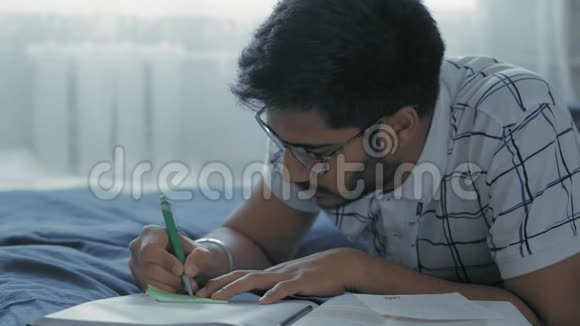 特写镜头戴眼镜的印度学生在宿舍里躺在床上视频的预览图