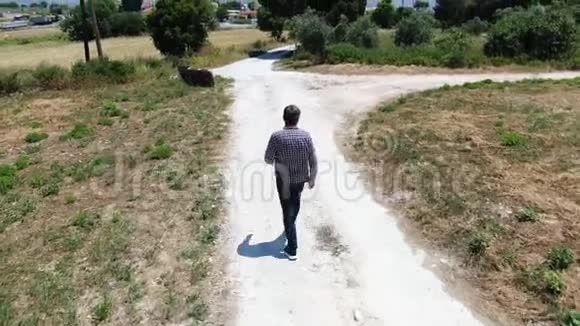 上面的视频是一个穿着牛仔裤格子衬衫和太阳镜的男人沿着乡村道路行走克朗追求视频的预览图