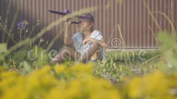 一个漂亮可爱的小女孩在篱笆下的草地上玩小飞机的肖像孩子视频的预览图