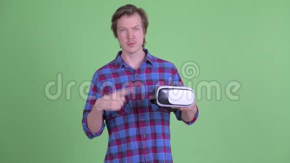 年轻英俊的嬉皮士拿着虚拟现实耳机指指点点视频的预览图