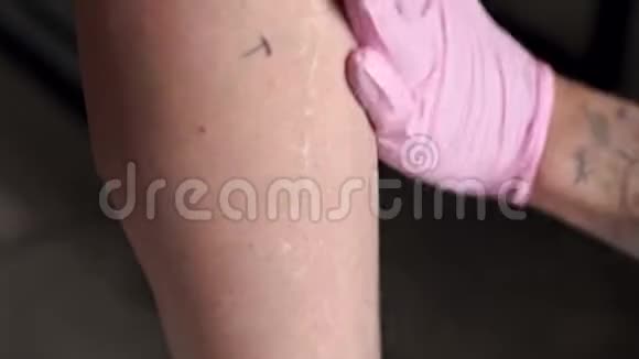 纹身师在工作前将无菌溶液雾化到客户腿上视频的预览图