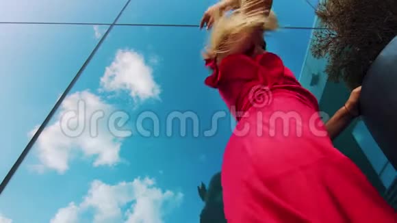都市环境中穿红色裙子跳舞的性感女人的低角度镜头视频的预览图