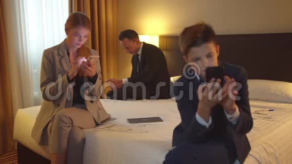 家庭在旅馆房间打电话母亲父亲和小男孩穿西装视频的预览图