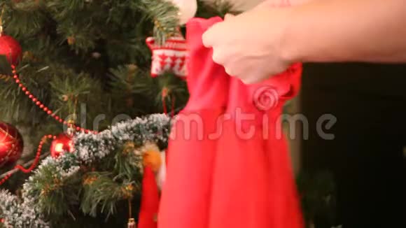 女人的手拿着看上去是一个小女儿参加圣诞聚会的红色裙子背景上的圣诞树视频的预览图