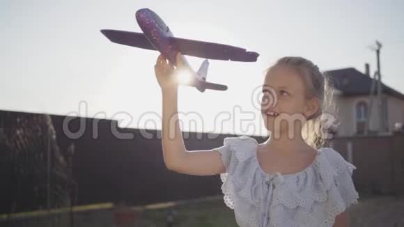 肖像可爱的小女孩抱着小玩具飞机特写孩子在后院里呆在户外视频的预览图