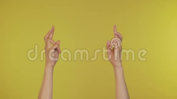 手指交叉的女孩年轻时一个手指祈祷好运的女人被孤立在黄色的背景上4K视频的预览图