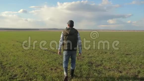 戴着帽子的农夫红脖子正走在绿色的田野上生活方式春季收获农业概念男性行走视频的预览图
