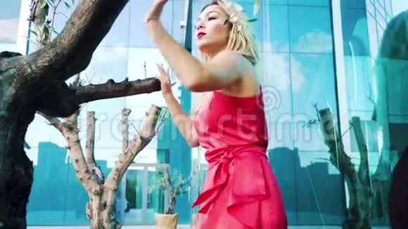 穿着红色裙子的金发美女在树和镜面附近跳舞视频的预览图