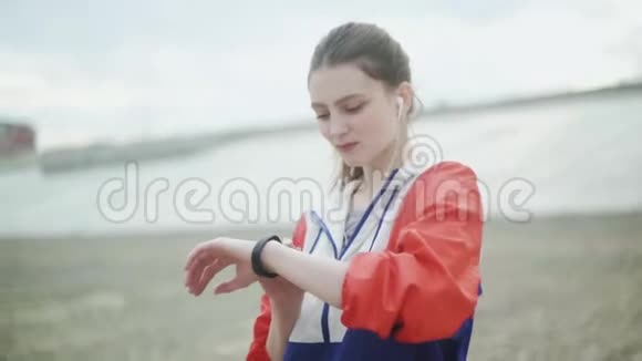 带着智能手表慢跑的女孩戴着智能手表的女士戴着耳机视频的预览图
