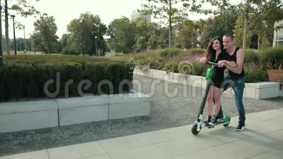 美丽的情侣女孩和男人在公园里骑电动滑板车视频的预览图