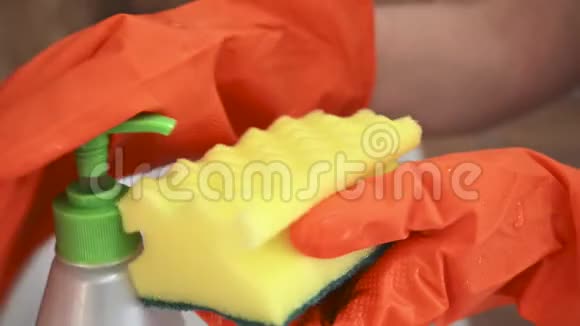 一只戴着橙色手套的女性手把洗涤剂放在海绵上冲洗厨房水槽上的盘子是家庭式的吗视频的预览图