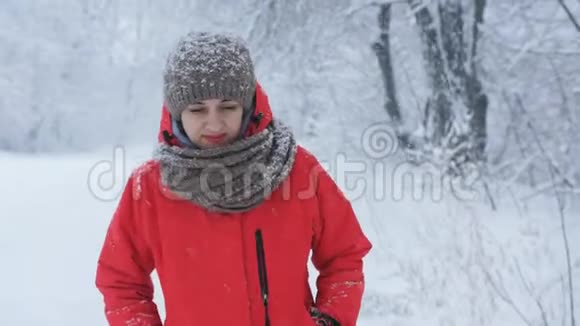 穿着红色夹克的女人在白雪覆盖的道路上镜头行走视频的预览图