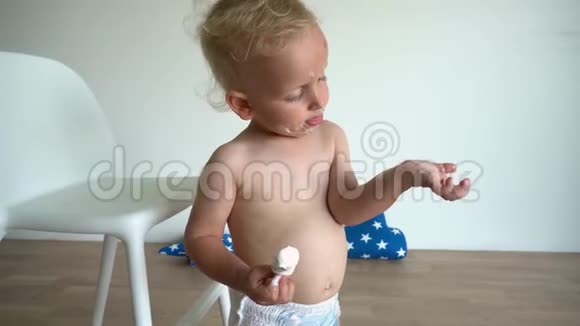 可爱的男婴脸上涂满了冰淇淋儿童尿布吃糖果视频的预览图